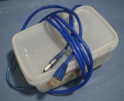 The Super Secret Sheep Server: Raspberry Pi in food container with hole at one end for USB power and hole at other end for Ethernet. Unfortunately, this arrangement requires opening the lid to program a ROM or microcontroller.